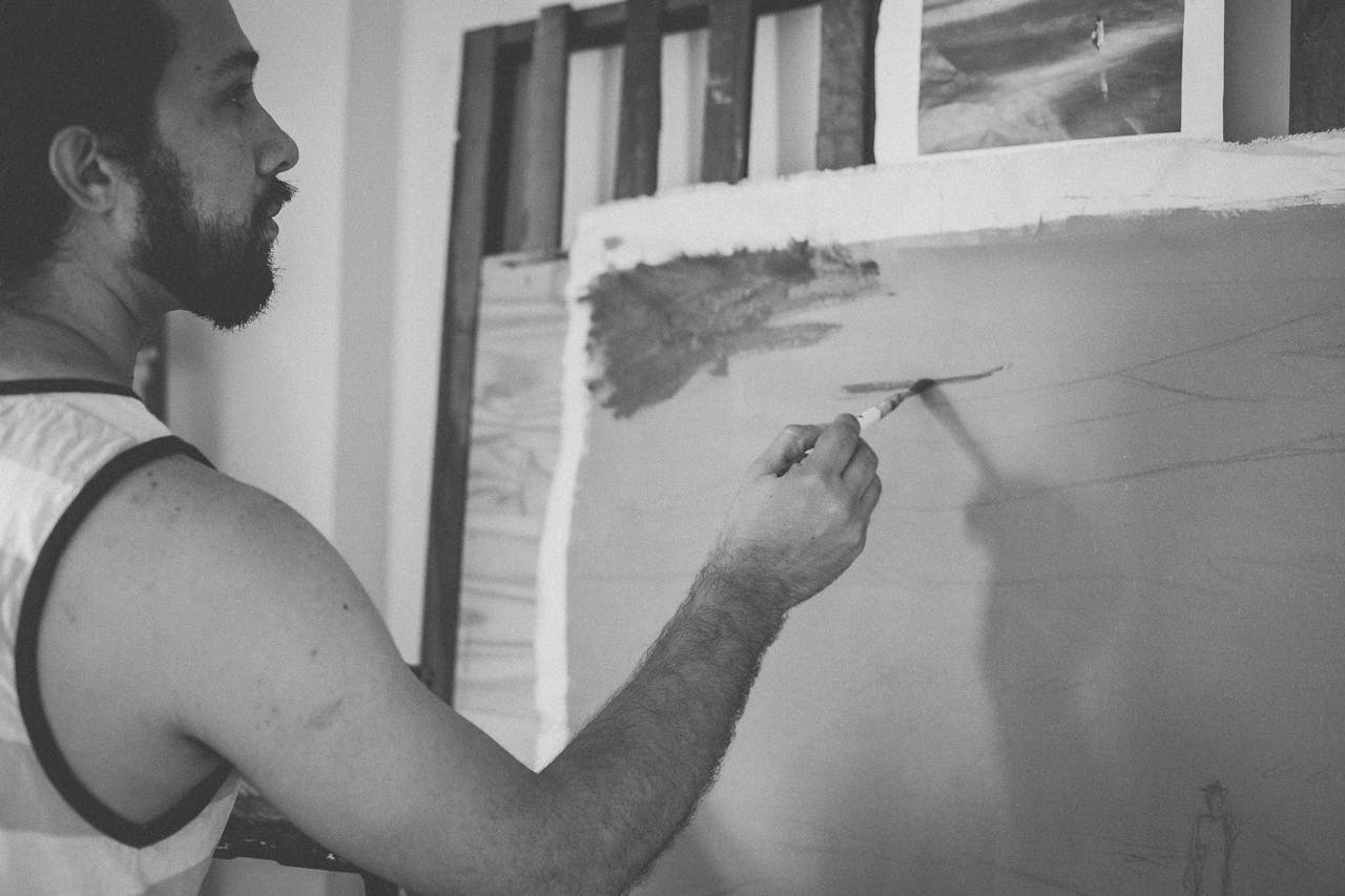 Artist intensely focusing on creating artwork in a studio with a brush and canvas.